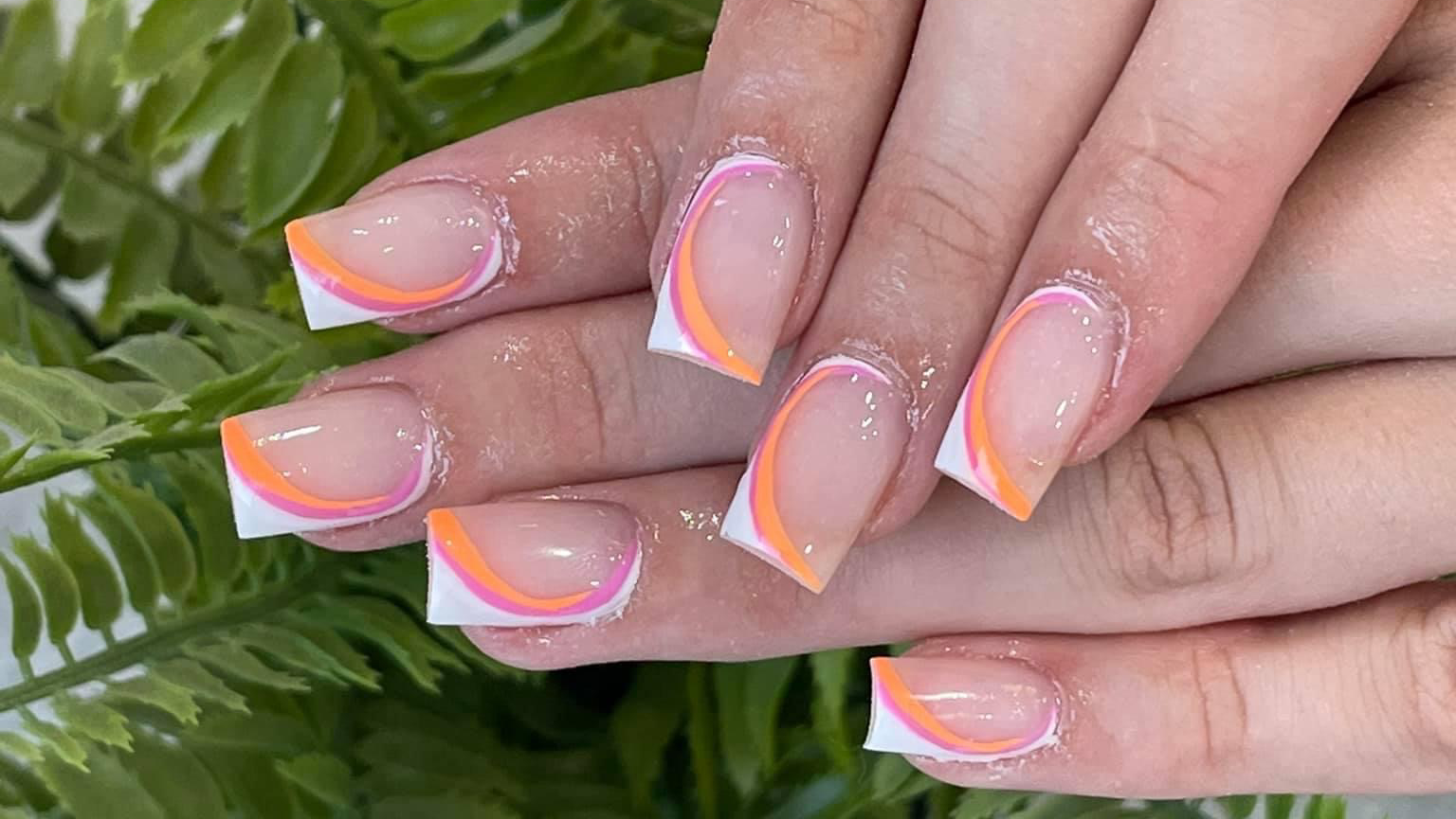 Orange and white curved French tips over fern leaves