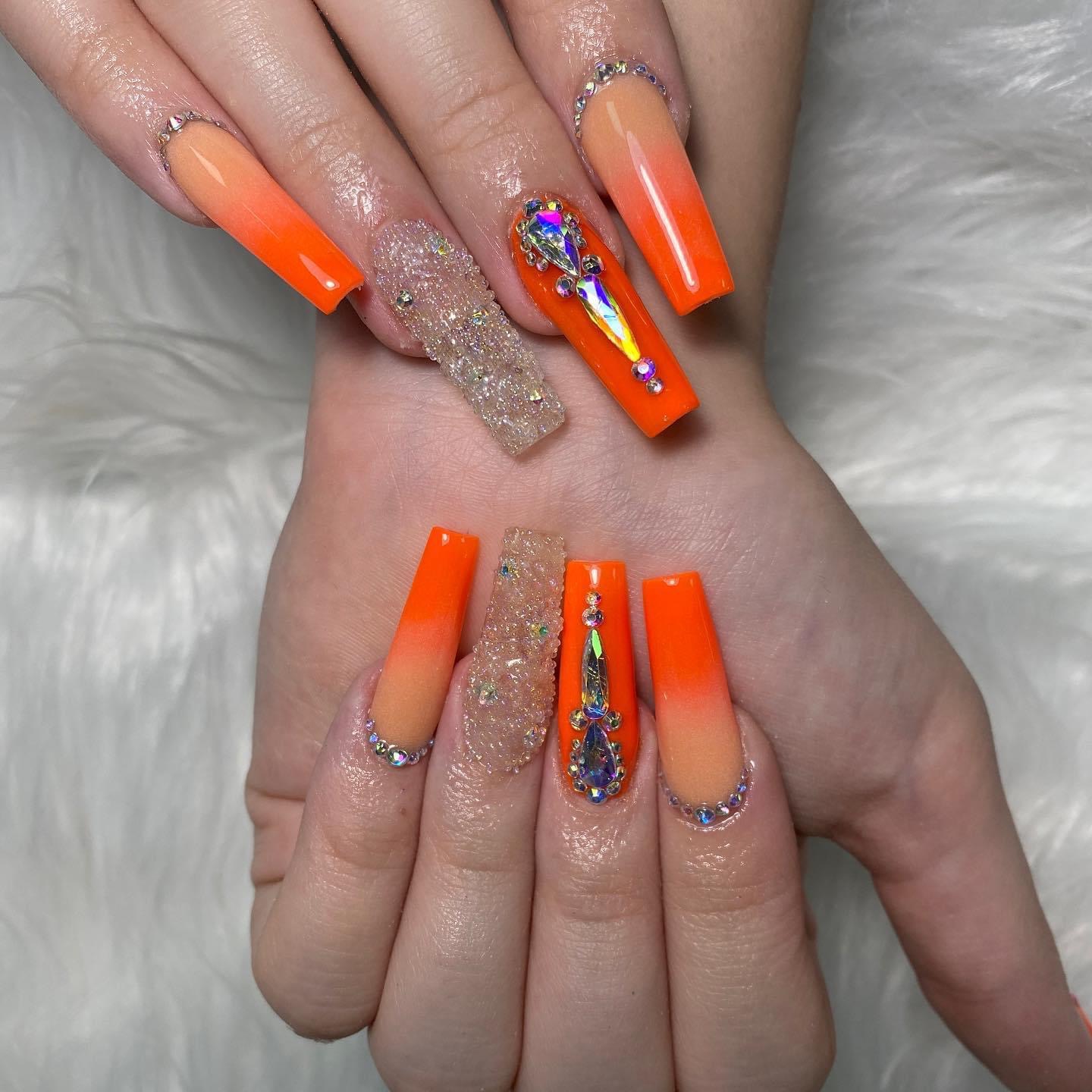 Orange ombré nails with crystal-covered accent nails