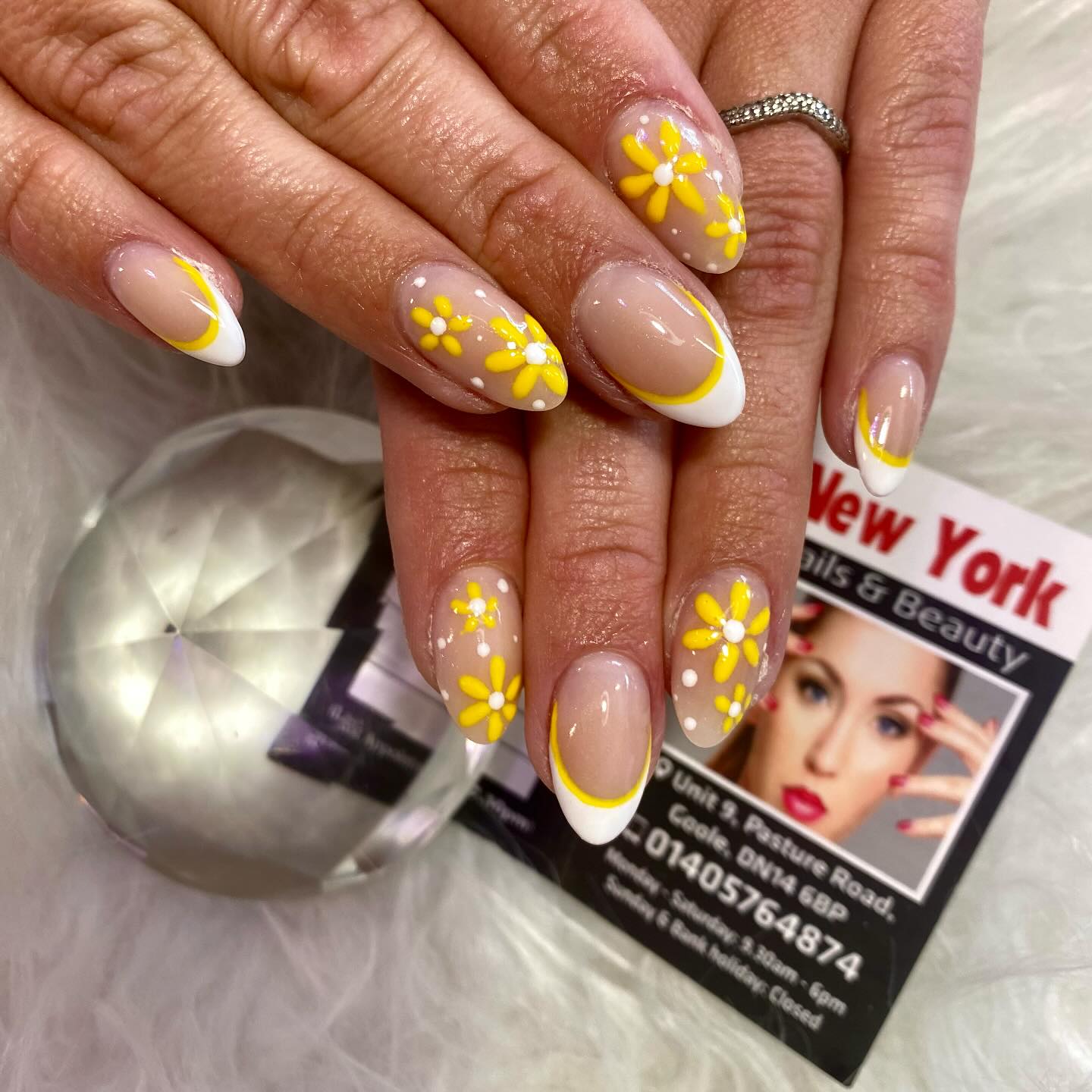 Nude nails with yellow French tips and daisy art